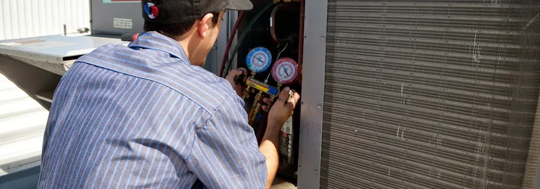 HVAC technician servicing a condenser unit in West Springfield